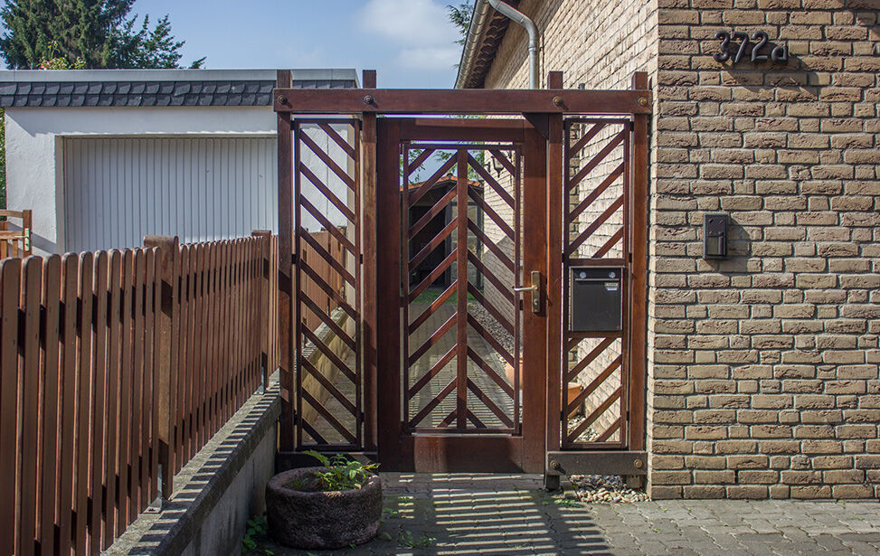 Holztor mit diagonalen Streben und Briefkasten