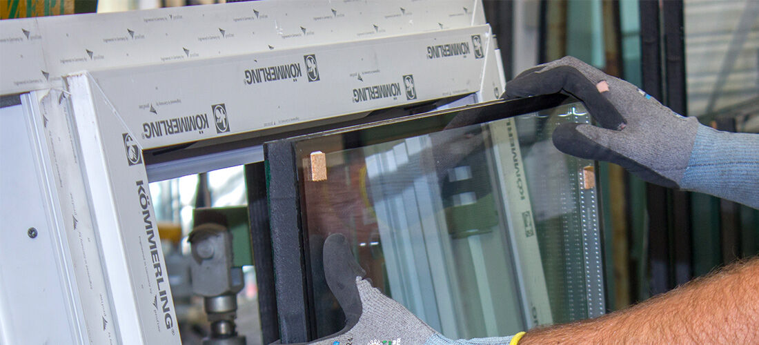 Monteur setzt eine Glasscheibe in einen KÖMMERLING-Fensterrahmen ein
